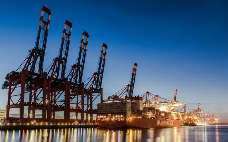 Container cranes and a ship in a port at dusk