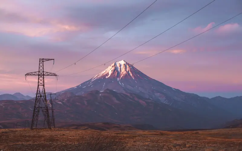 High-voltage pylons in front of a mountain at dusk